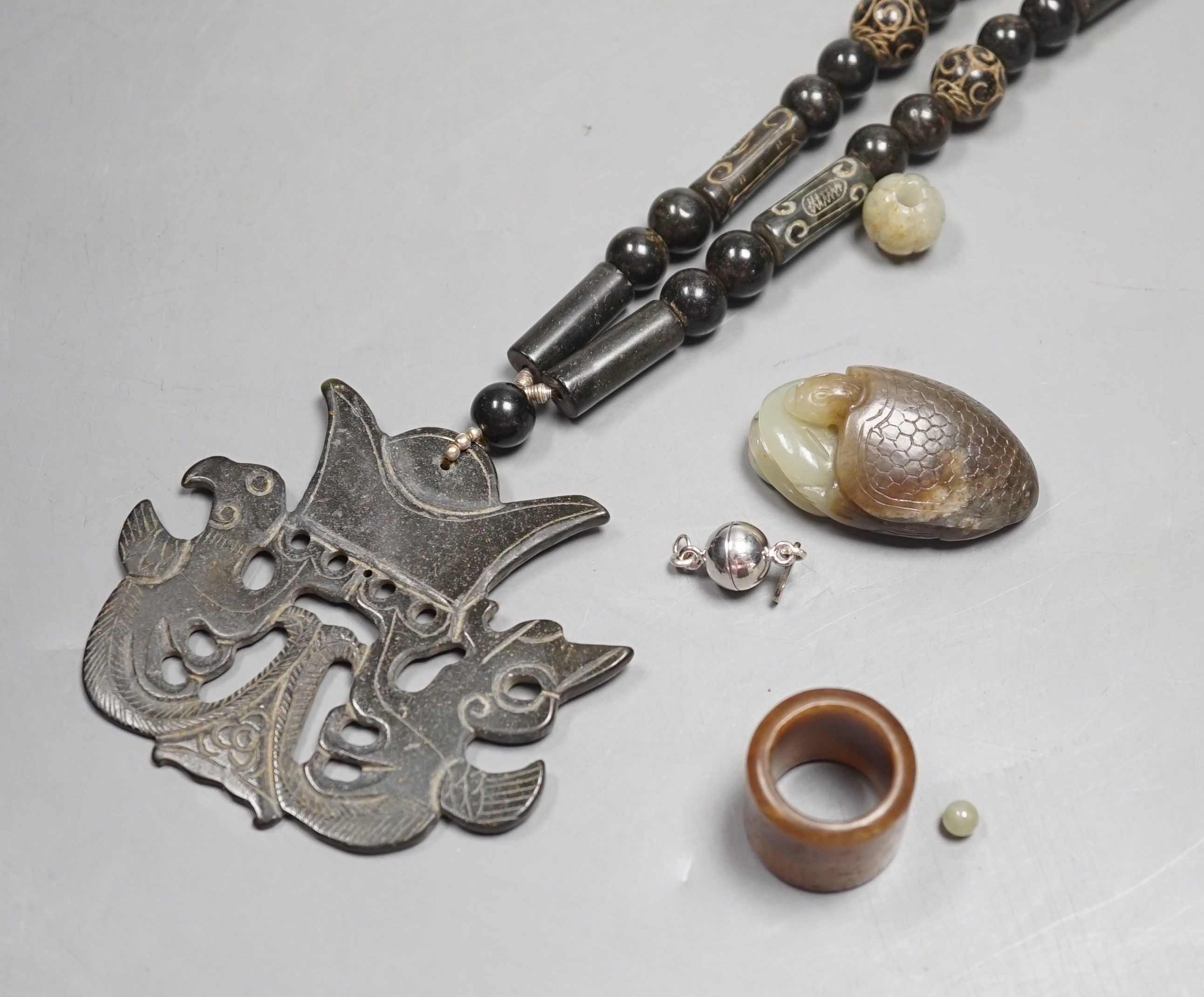 Kai Yin Lo of Hong Kong, a jade turtle and snake pendant, jade archer’s ring and two beads, formerly strung on a necklace together with a hardstone necklace